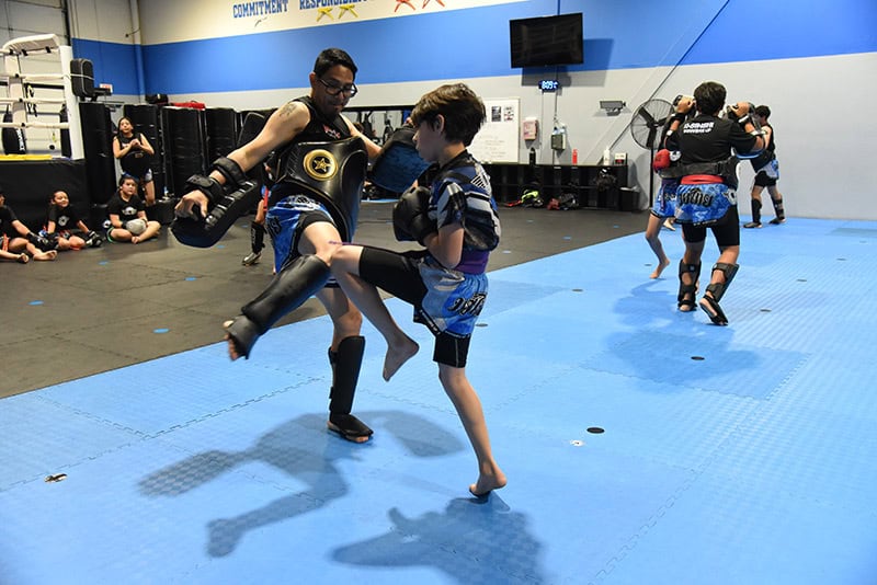 A young student practices a kick drill with a coach during kids martial arts class at Ki-Senshi in Chandler, AZ.