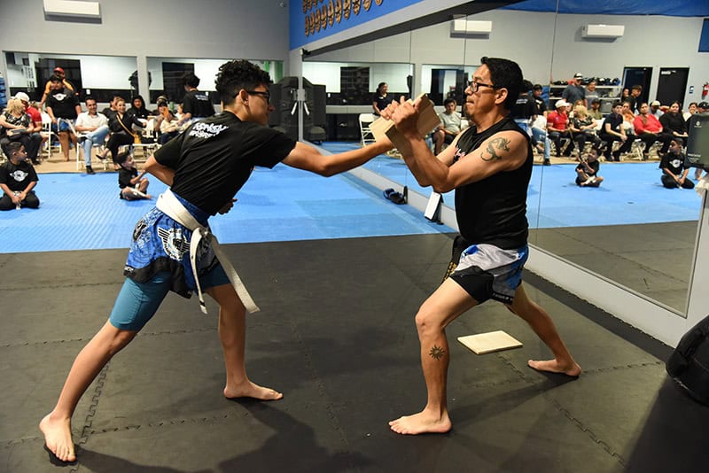 A teen student practices board breaking with a coach at Ki-Senshi Martial Arts in Chandler, AZ.