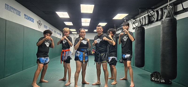 Teen students and an instructor stand in fighting stance after a martial arts training session at Ki-senshi Martial Arts.